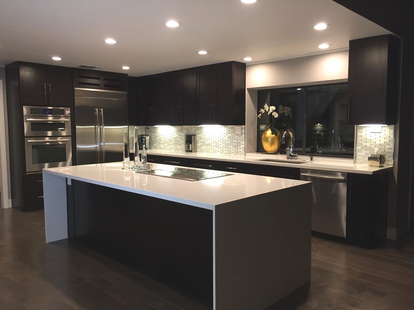 Modern kitchen with dark cabinets and white countertops.