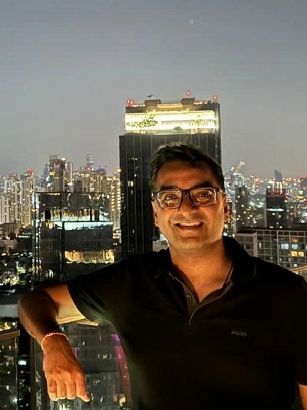 Man smiling with city lights in the background at night.