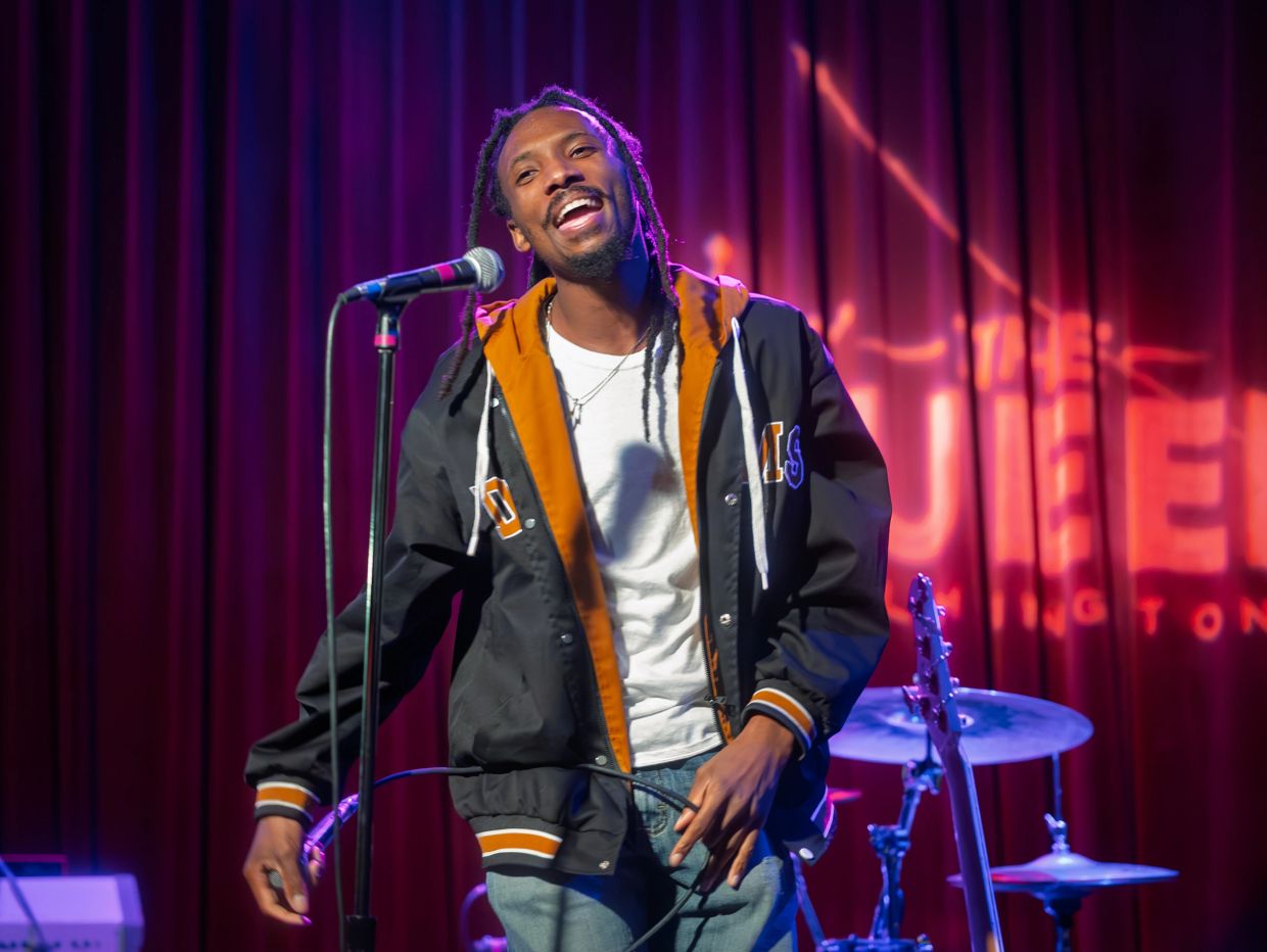 Young man singing on stage with microphone.