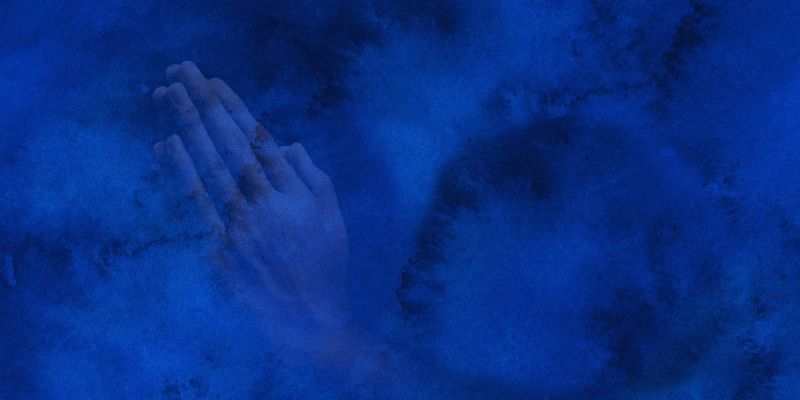 A pair of hands pressed together in prayer, surrounded by blue mist.