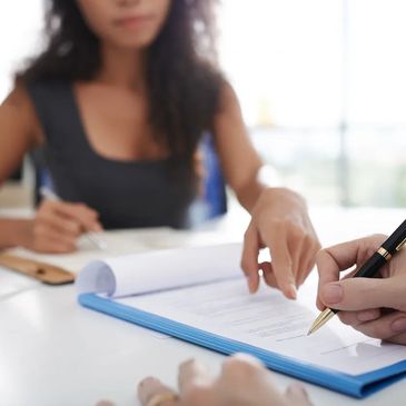 brown girl showing someone where to write on a paper