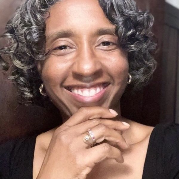 Close-up of a smiling person with curly hair.