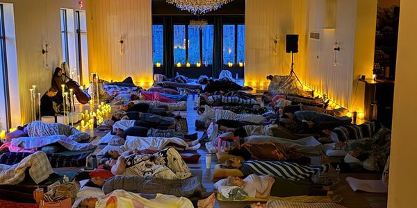People lying down for a relaxing session with live cello music and candlelight.