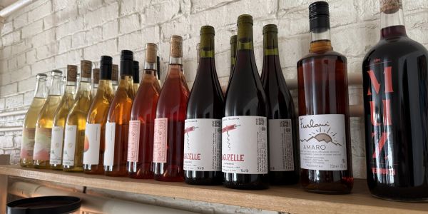 A row of wine and liquor bottles on a wooden shelf.