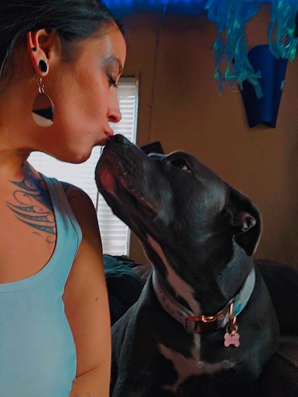 Woman and dog sharing a loving kiss indoors.