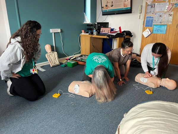 Group of people CPR First Aid Training course. CPR teen dummy first aid training.
