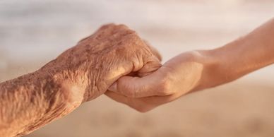 An individual of middle age offering a supportive grip to an elderly person.