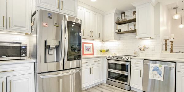 Modern kitchen with stainless steel appliances, white cabinets, and quartz countertops