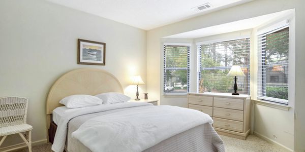Guest bedroom with a queen bed, bay window, and neutral decor in a Hilton Head vacation home.