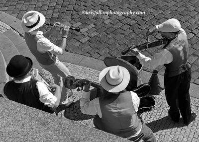 Black and white photo of a four-piece band playing instruments outdoors.