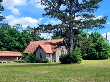 Wooden house with red roof surrounded by trees.