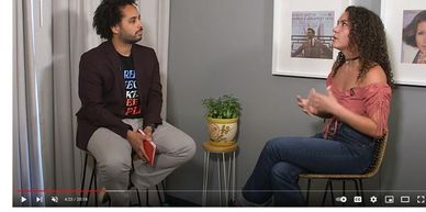 Two people engaged in a seated conversation in an indoor setting.