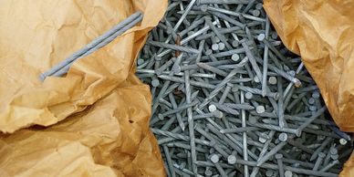 A heap of metal nails in a paper bag.