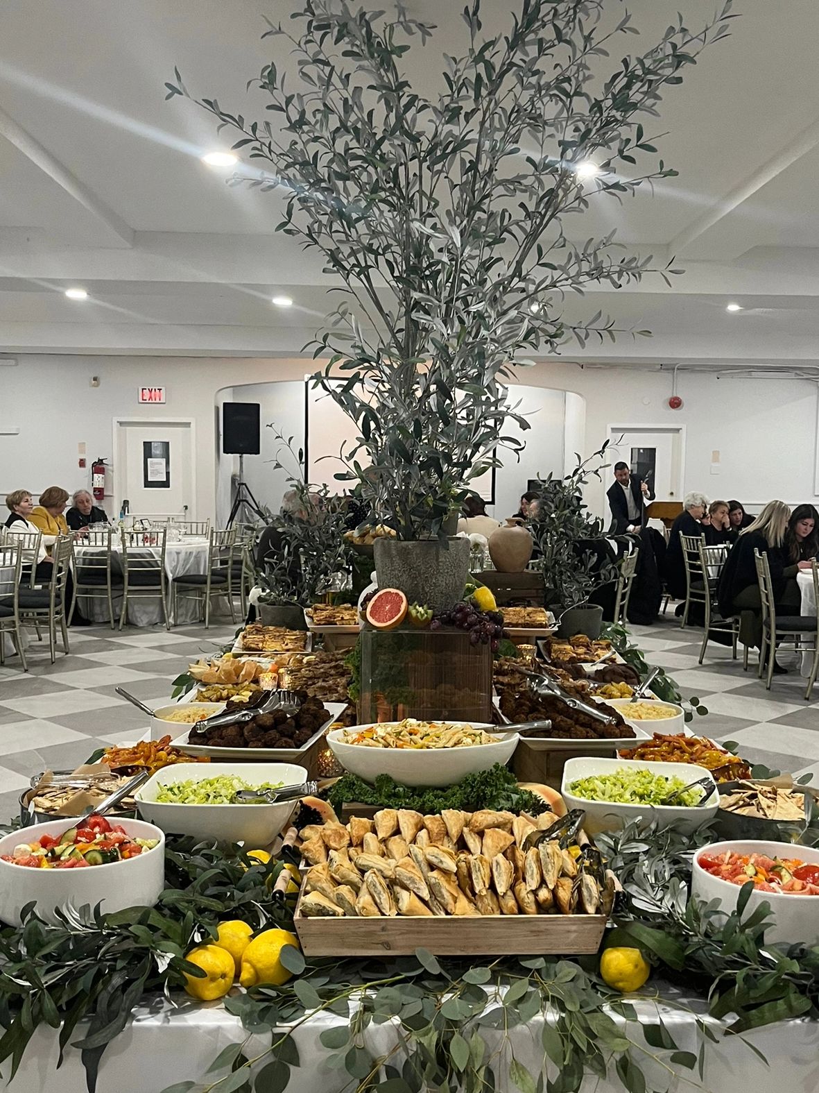An elegant buffet setup with greenery and a variety of dishes in a banquet hall.