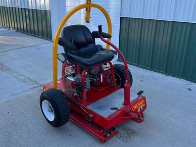 A red riding lawn mower parked on a concrete surface.