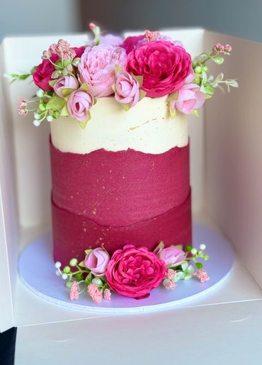 Elegant two-tone cake decorated with vibrant pink flowers on top and base.