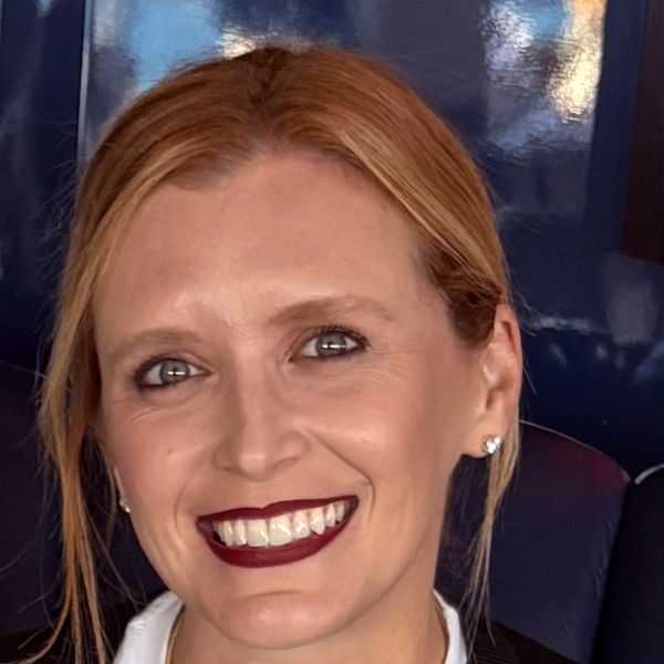 Smiling woman with red hair and dark lipstick.
