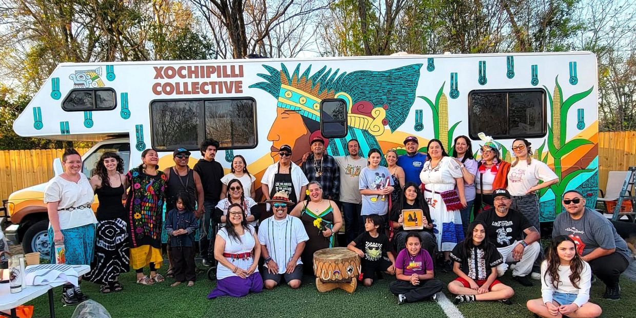Group of people posing in front of a colorful Xochipilli Collective van.
