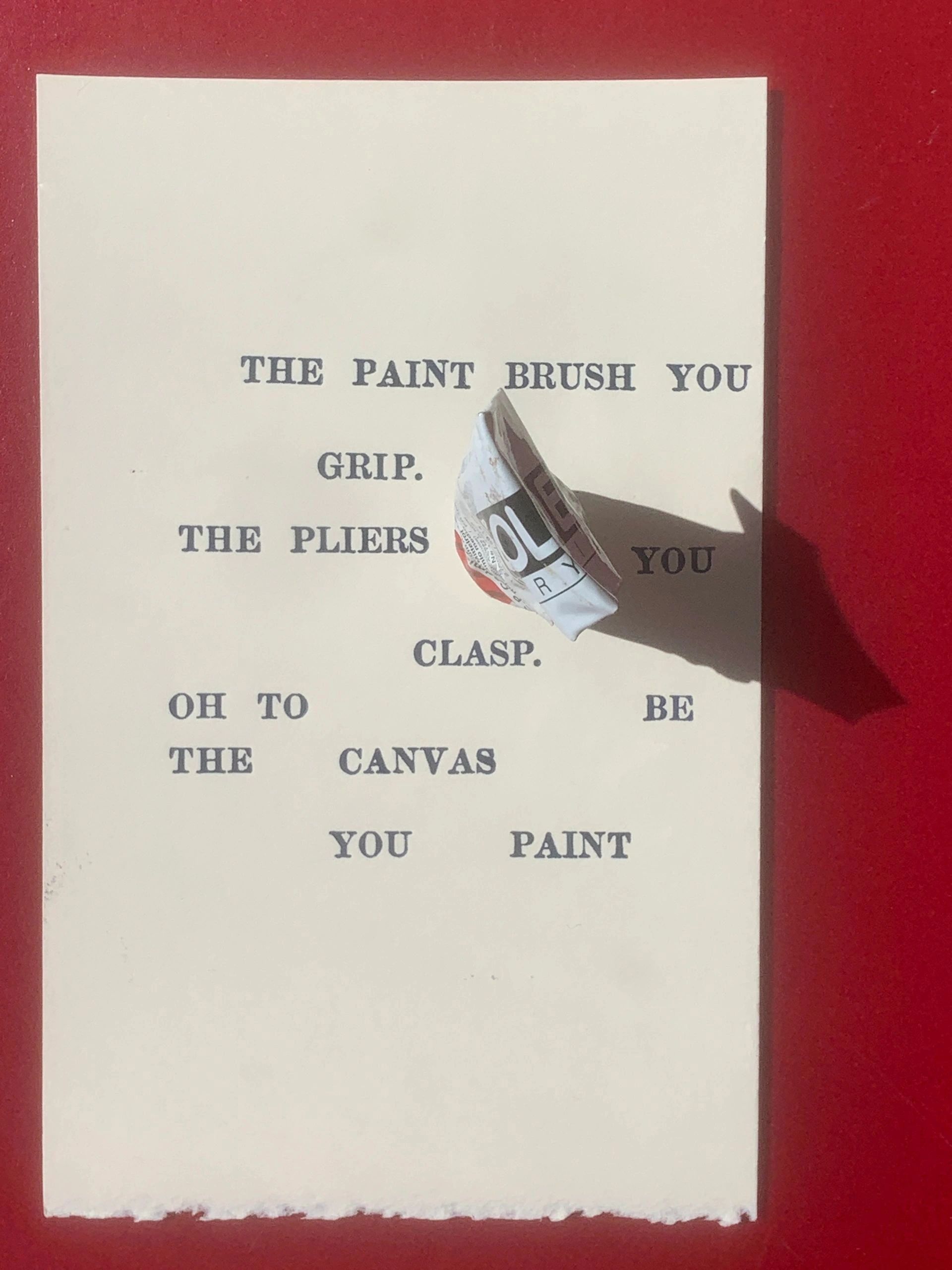 A crumpled paint tube on a typed poetic text on white paper with a red background.