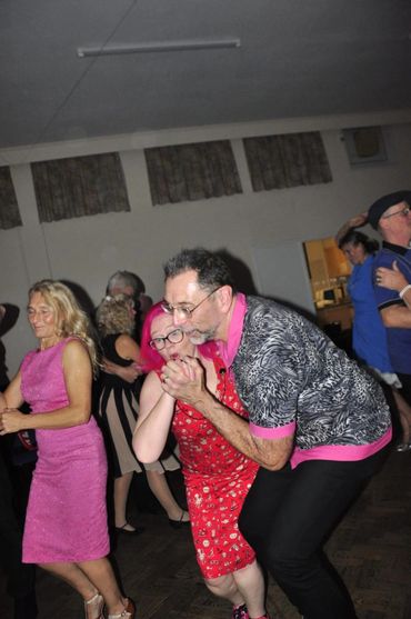 Couples dancing joyfully at an indoor event.