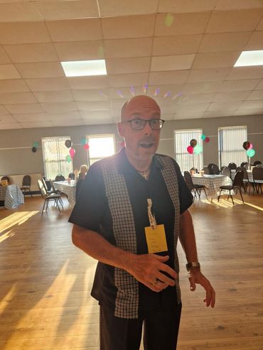 Man with glasses and a surprised expression in a decorated room with balloons.