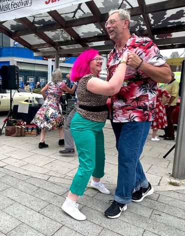 A joyful couple dances outdoors at a lively music festival.