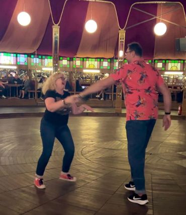 A joyful couple dancing energetically in a vintage dance hall.