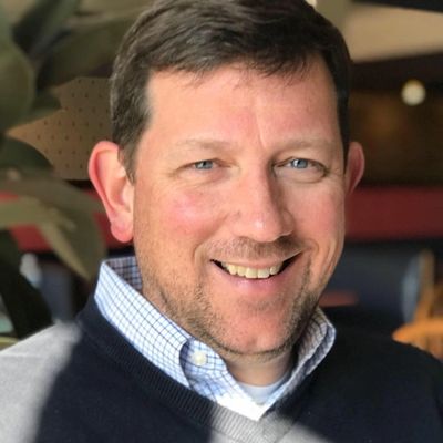 Smiling man with blue eyes in a cozy indoor setting.