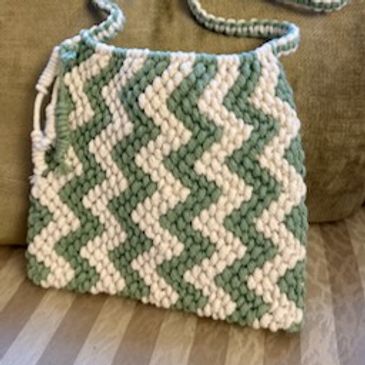 Handwoven bag with green and white zigzag pattern and braided strap.