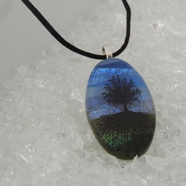 Pendant with tree on sky and grass background.