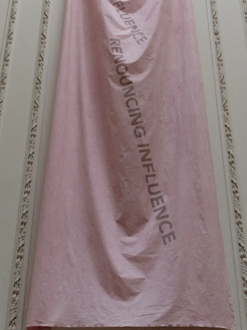 Pink banner hanging on a wall with text.