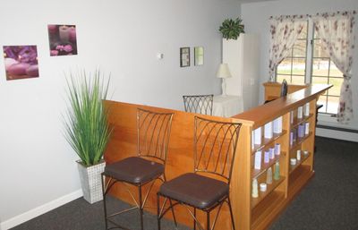 Front desk, spa pictures, plants, retail products, rod-iron chairs, cabinet & window