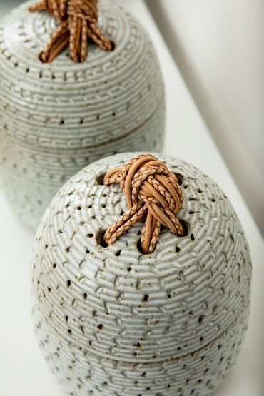 carved stoneware jars with braided leather knots