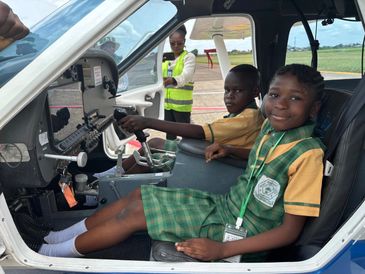 Two kids sitting in a small airplane cockpit.