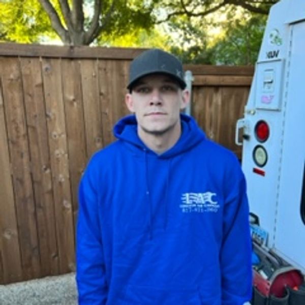 Man in blue hoodie and black cap standing outdoors.