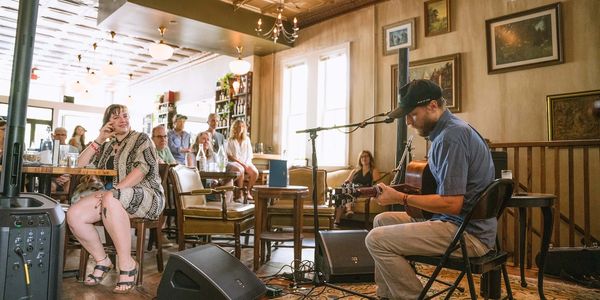 A man plays guitar in a cozy cafe while people listen.