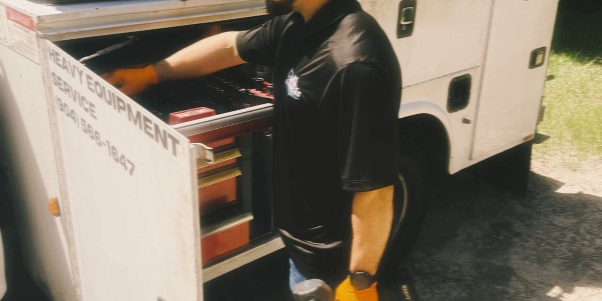 Worker opening heavy equipment truck drawer.