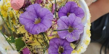 Purple flowers in a small container with powder.