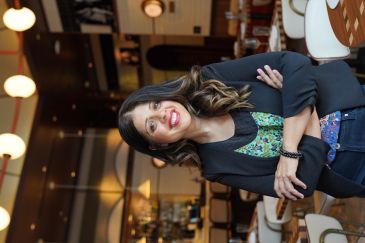 Confident woman smiling in a stylish restaurant with arms crossed.