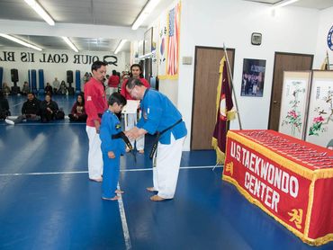 Man presenting a black belt to a child.