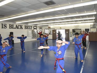 Kids in blue taekwondo uniform training.