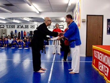 Man presents certificate in taekwondo class.