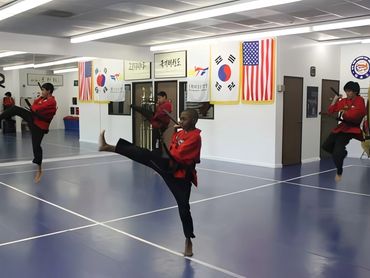Group of three Taekwondo students performing high kicks.