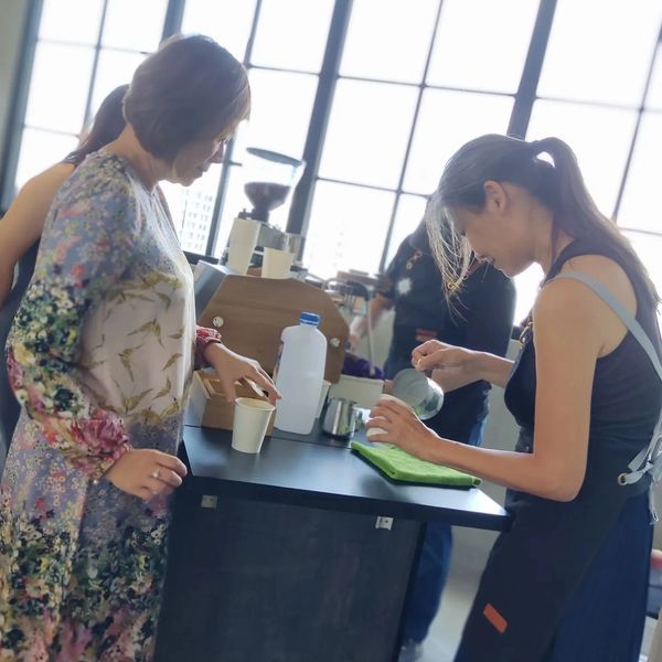 Woman serving coffee to a customer at a cafe counter.