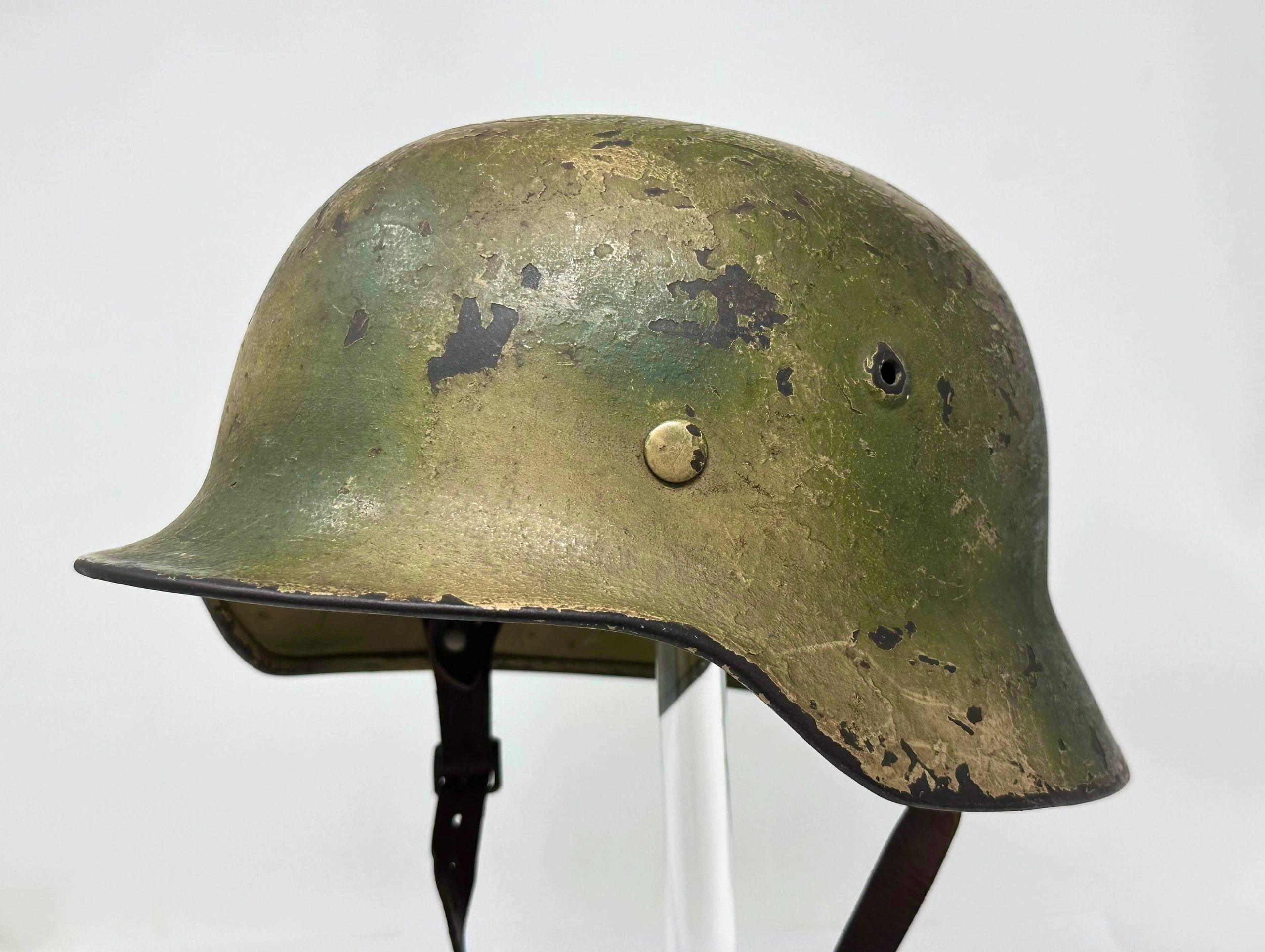 Worn military helmet with camouflage paint.