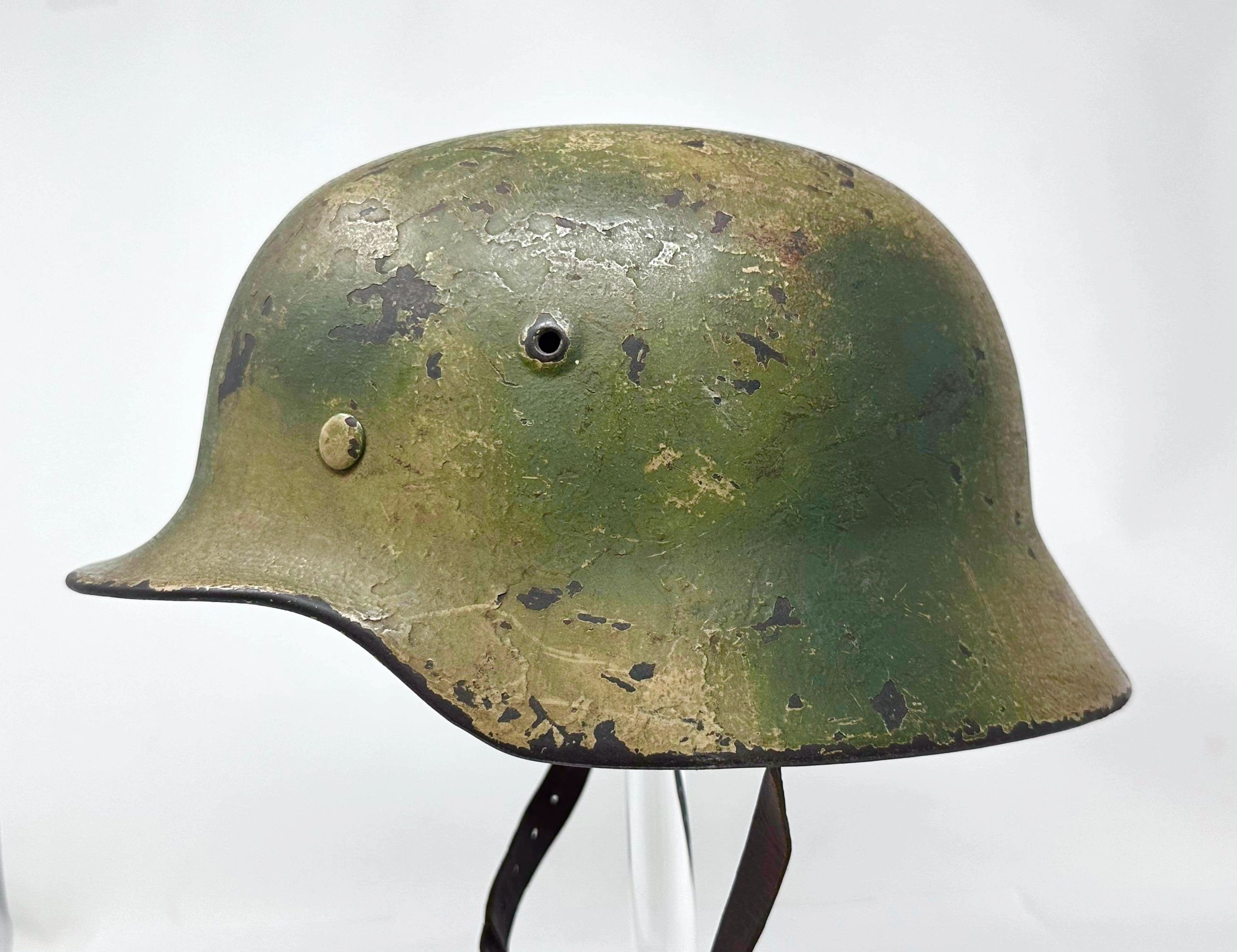 Worn green military helmet with chin strap.