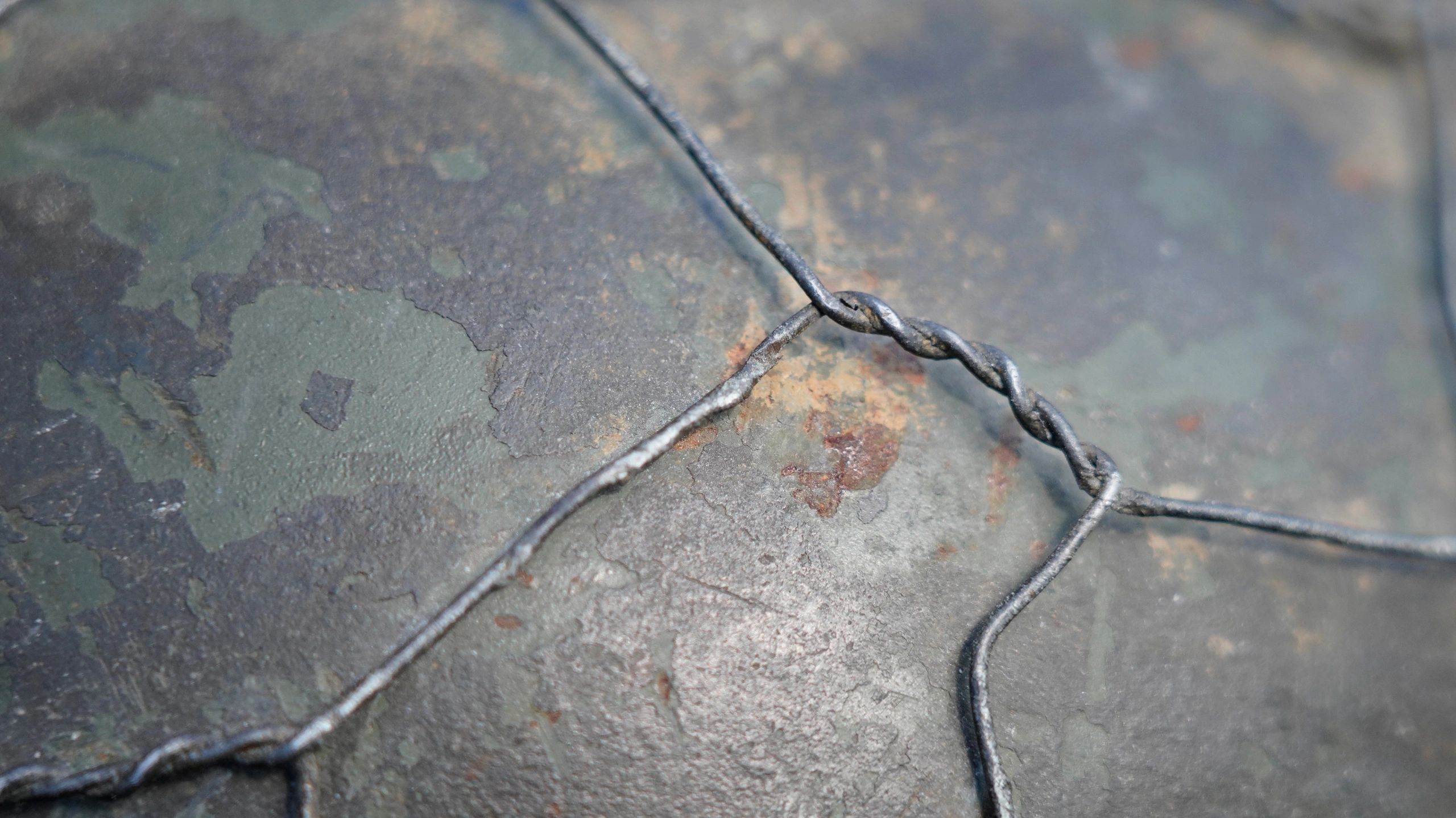 Close-up of twisted wire on a weathered, painted metal surface.
