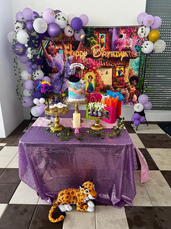 A vibrant Encanto-themed birthday setup with balloons and a plush leopard.