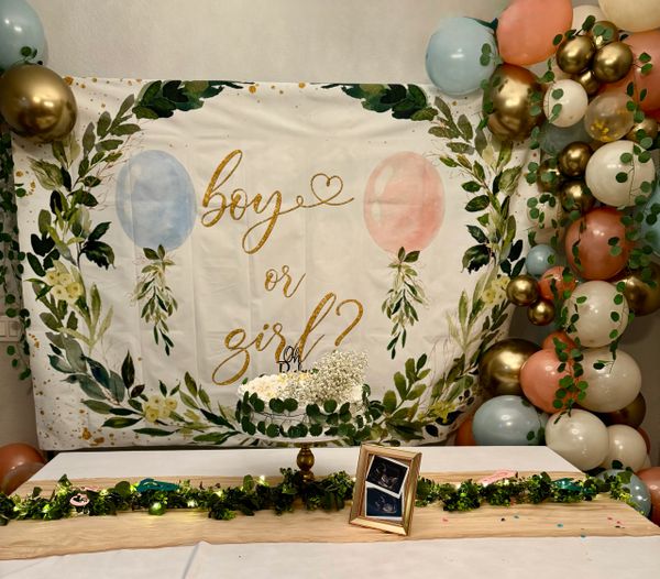 Gender reveal party setup with balloons and a cake.