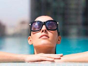 Women coming out of a pool with big black sunglasses 